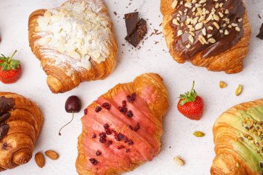 Beyaz arka planda farklı tatlı kruvasanlar ve meyveler.