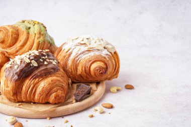 Beyaz arka planda farklı tatlı kruvasanları olan ahşap tahta.