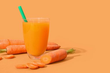 Turuncu arka planda bir bardak taze havuç suyu