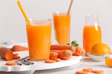 Bardaklar ve beyaz zemin üzerinde portakal suyu olan taze havuç suyu.
