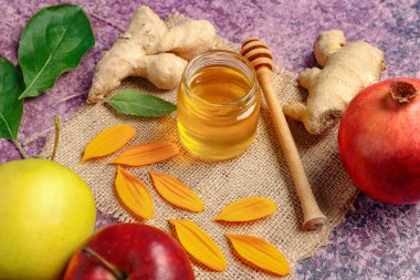 Mor arka planda zencefilli, elmalı ve narlı bal kavanozu.