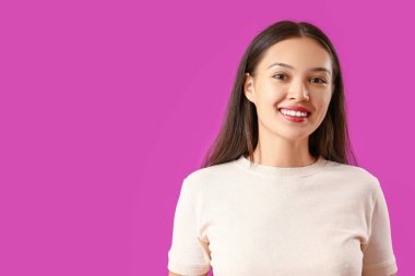 Mor arka planda sağlıklı dişleri olan gülümseyen genç Asyalı kadın.