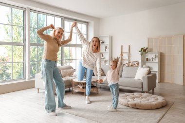 Annesi ve büyükannesiyle dans eden tatlı küçük bir kız.