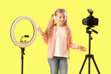 Sarı arka planda halka ışığı kayıt videosu olan kulaklıklı genç blogcu