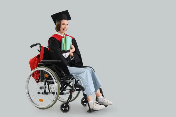 stock image Female graduate in wheelchair with books on light background