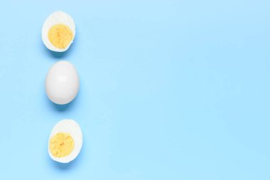 Lezzetli haşlanmış yumurta, mavi arka planda yarımlar.