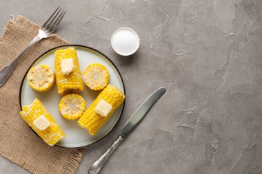 Gri arka planda tereyağlı haşlanmış mısır koçanı tabağı