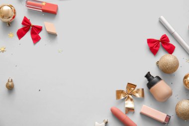 Dekoratif kozmetik ürünleri ve gri arka planda Noel dekoru olan kompozisyon