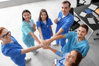 Bir grup tıp öğrencisi üniversitede el ele tutuşuyor.