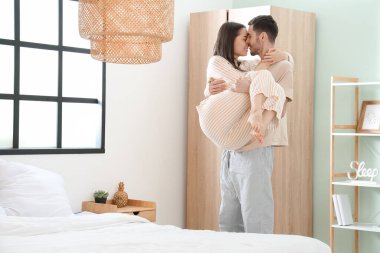 Genç adam yatak odasında kız arkadaşını tutuyor.