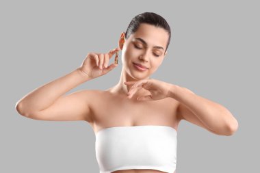 Gri arka planda ampul tutan güzel genç bir kadın.