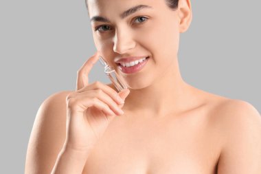 Gri arka planda ampul tutan güzel genç bir kadın.