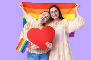 LGBT bayrakları ve eflatun arkaplanda kağıt kalpli güzel bir lezbiyen çift.