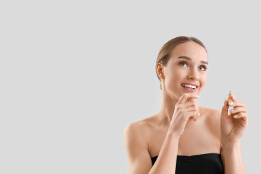 Hafif arka planda ampulü olan düşünceli genç bir kadın, yakın plan.