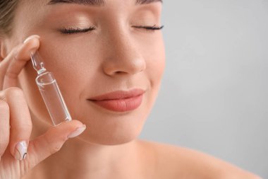 Işık arka planında ampulü olan güzel genç kadın, yakın plan.