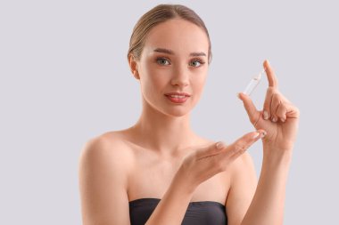 Işık arka planında ampulü olan güzel genç kadın, yakın plan.