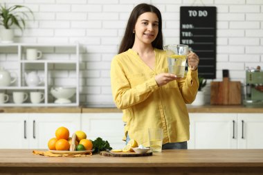 Mutfakta bir sürahi limonlu suyla güzel bir genç kadın.