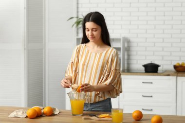 Mutfakta meyve suyu hazırlamak için portakal sıkan güzel bir kadın.