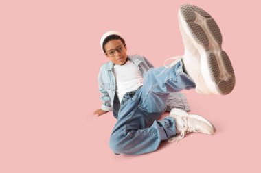 Pembe arka planda yetişkin kıyafetleri giymiş küçük Afro-Amerikalı çocuk.