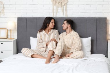 Pijama yatağa evde oturan genç Çift