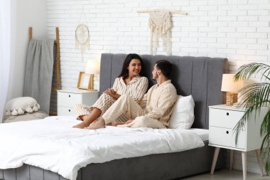 Pijama yatağa evde oturan genç Çift