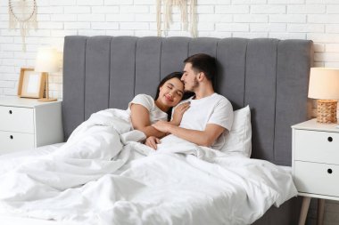 evde yatakta yatan sevgi dolu genç Çift