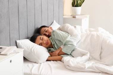 Kocasıyla birlikte yatak odasında uyuyan genç bir kadın.