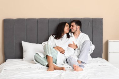 Mutlu genç çift yatak odasında oturuyor.