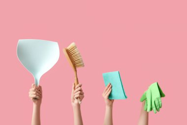 Faraş, süpürge, lastik eldiven ve pembe arka planda paçavra tutan kadın elleri.