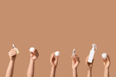 Şişeli kadın elleri ve bej arka planda kozmetik ürünleri kavanozları