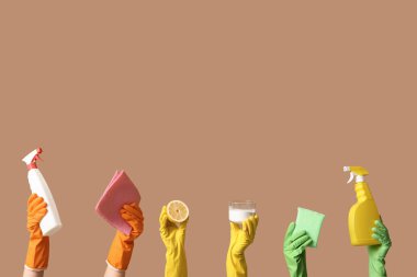 Deterjan, bez, sünger, limon ve kavanoz şişelerini tutan kadın elleri kahverengi arka planda temizlik maddesi var.