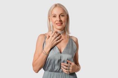 Beyaz arka planda güzel takılar takan modaya uygun olgun bir kadın.