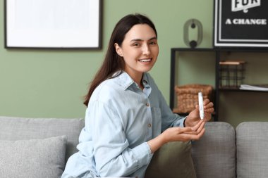 Şeker hastası genç bir kadın evdeki kanepede tükenmez kalem kullanıyor.