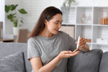 Şeker hastası genç bir kadın evdeki kanepede tükenmez kalem kullanıyor.