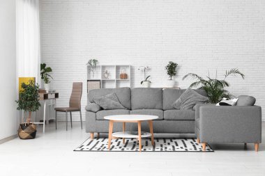 Gri kanepesi, koltuğu ve masası olan şık bir oturma odası.