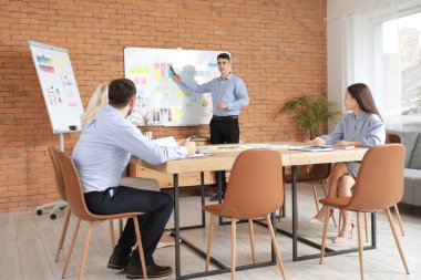 Genç adam iş planı üzerinde çalışıyor. Ofisteki iş arkadaşlarıyla birlikte.