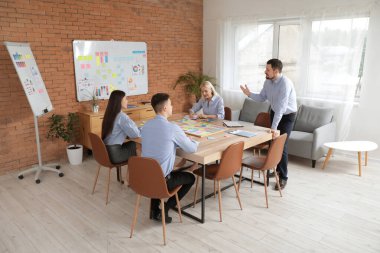 Genç adam ofisteki meslektaşlarıyla iş planını tartışıyor.