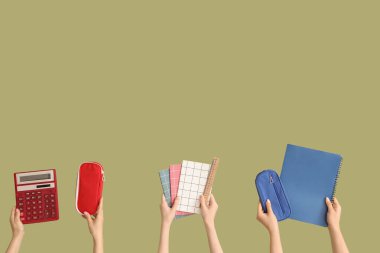 Yeşil arka planda okul ekipmanları olan kadın eller.