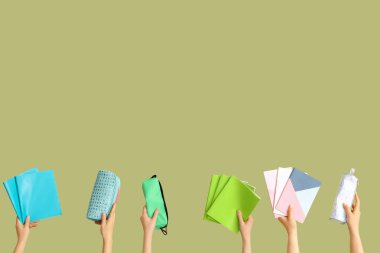 Yeşil arka planda okul ekipmanları olan kadın eller.