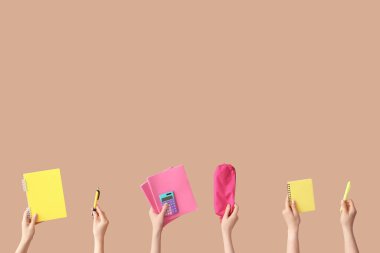 Bej arka planda okul ekipmanları olan kadın eller.