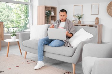 Evde termometre görüntülü konuşan hasta genç adam.