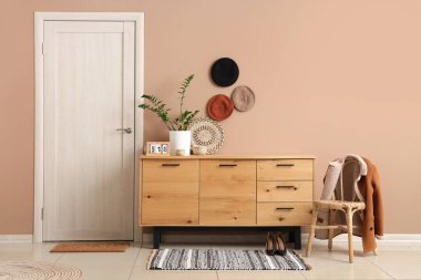 Askısı, büfesi ve ceketli sandalyesi olan modern salonun şık iç tasarımı.