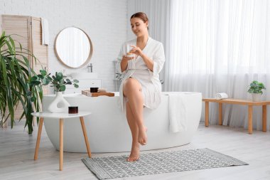 Banyoda krema kavanozu olan güzel ve iri yarı bir kadın.