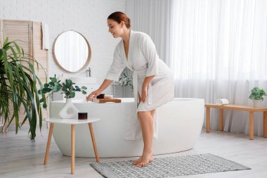 Güzel ve kilolu bir kadın banyodaki masadan anti-selülit fırçasını alıyor.