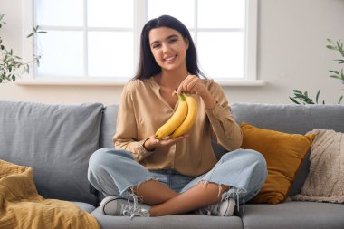 Evdeki kanepede muzlu genç bir kadın oturuyor.