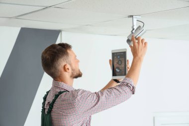 Tablet bilgisayarlı erkek işçi odaya alarm sistemi kuruyor
