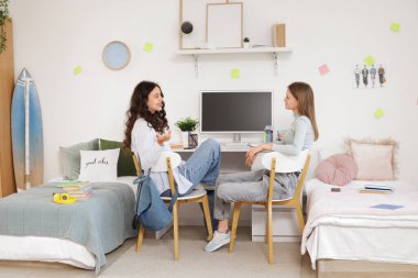 Yurt odasındaki masada konuşan kız öğrenciler.