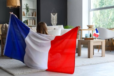 Fransa bayrağı taşıyan genç bir kadın halının üzerinde oturuyor.