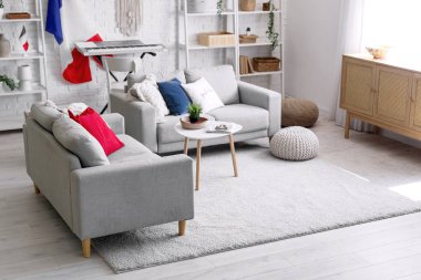 Oturma odasının içinde kanepeler, raf üniteleri ve Fransız bayrakları var.