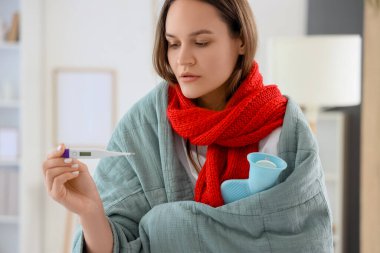 Evde termometresi ve sıcak su şişesi olan hasta genç bir kadın var.